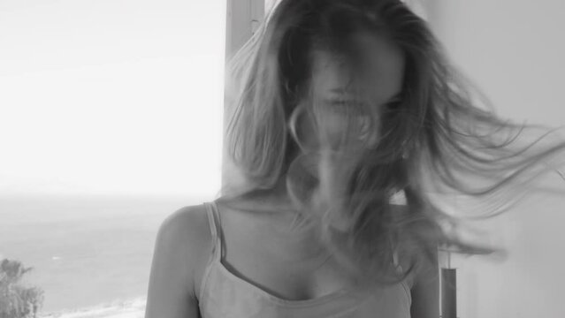 Woman in hotel room loosens her hair and shakes it while smiling