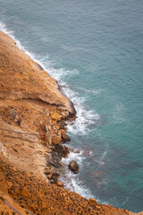 waves hitting against the cliffs on the outskirts of Benidorm, Image shows a dark cloudy day with a...