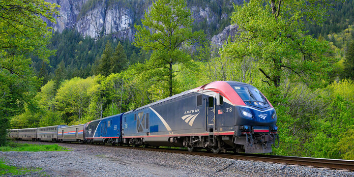 Index, WA, USA - May 1, 2024; Amtrak Empire Builder passenger train in rural Cascade Mountain Range with green trees