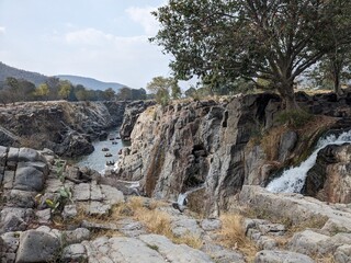 Beautiful river with cascading rocks, a cascade, and boaters taking in the scenery.