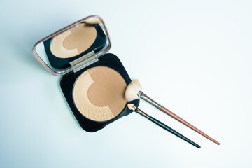 A small makeup kit with a mirror and with bronzing powders and two different types of brushes to apply them on the face