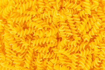 Close up of uncooked yellow Rotini pasta for a background. Ingredient for a delicious italian meal