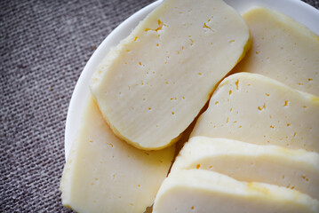 Slices of cheese cut on a plate. Delicious cheese with holes.