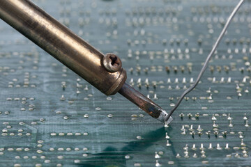 A soldering iron is carefully placed on the back of the circuit board to connect the soldering...