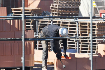 maçon posant des briques sur un chantier de construction d'un bâtiment d'habitation