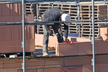 maçon posant des briques sur un chantier de construction d'un bâtiment d'habitation