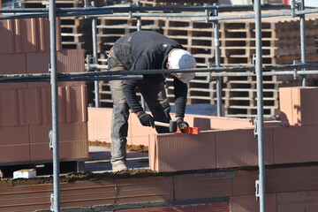 maçon posant des briques sur un chantier de construction d'un bâtiment d'habitation