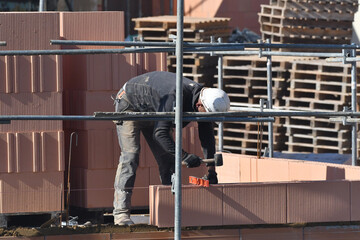 maçon posant des briques sur un chantier de construction d'un bâtiment d'habitation