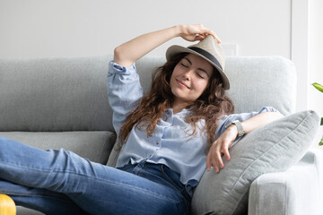 happy and relaxed woman lying on the sofa with her hat on waiting to go on summer vacation