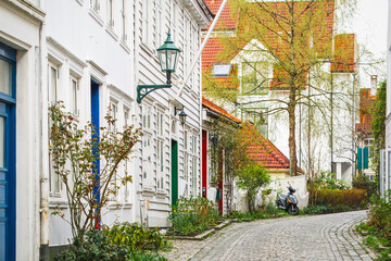 Charming cobblestone street lined with historic white wooden houses in the old town in spring. Bergen, Norway Heritage, sightseeing.