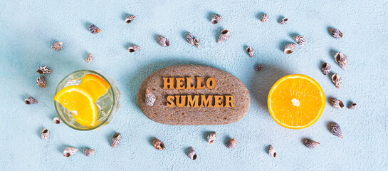 Concept hello summer text on stone, cocktail, orange and seashells on blue top view web banner