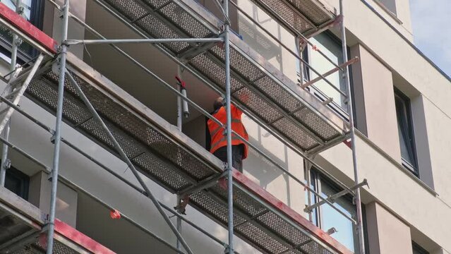 Reckless Construction Worker Without Protective Helmet Standing on Scaffolding Outside of Apartment Residential Building
