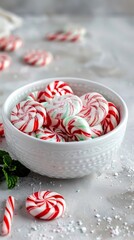 Peppermint candies in a white bowl with holiday decorations.