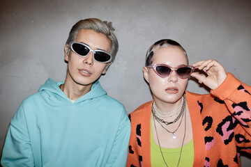 Portrait of two creative young couple wearing sunglasses and posing with flash