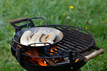 Grilling bratwurst sausages over flaming grill. Bearbeque outdoors. Barbecue Picnic