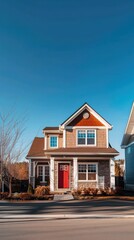 A modern two-story house with a striking red door and clear blue sky backdrop The home features a mix of textures and large windows