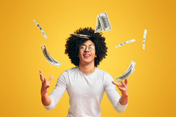 It's raining cash. Young black guy enjoying money shower, orange background