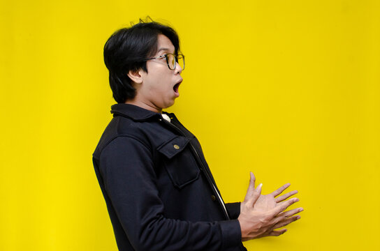 copy space side view of estactic attractive young asian man shocked happily opening mouth and lowering glasses. asian man with glasses feels shock with wow surprised expression