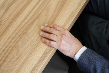 The hand of an adult man in a strict business suit lies on the edge of the table. Professional...