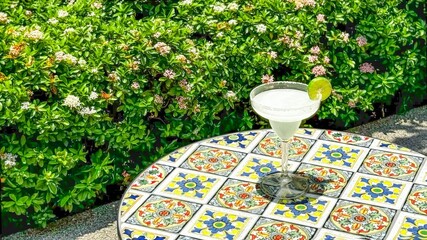 Refreshing low alcohol cocktail rests on mosaic table surrounded by lush greenery, capturing...