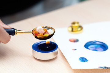 Hand with a melting spoon dissolving multicolored sealing wax