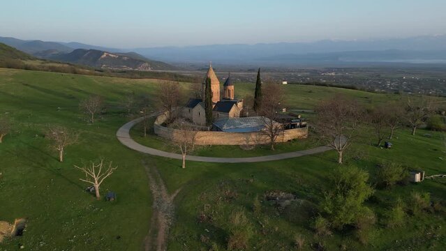 lonely ancient church in the mountains at dawn between green hills, aerial view
