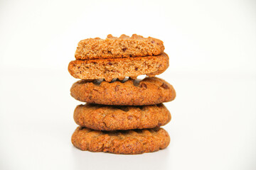 Stack of freshly baked peanut butter cookies. The top cookie is broken in half to see the texture of cookies. White background.