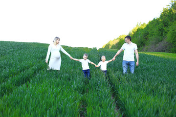 A family of four strolling through a lush green field. The image captures a moment of anticipation...