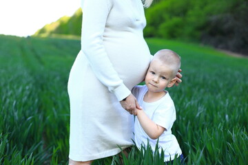 A pregnancy woman standing in a field with young boy. Expecting my third child. The woman is...