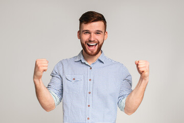 Fototapeta premium Cheerful guy showing his biceps and smiling on studio background, panorama, copy space