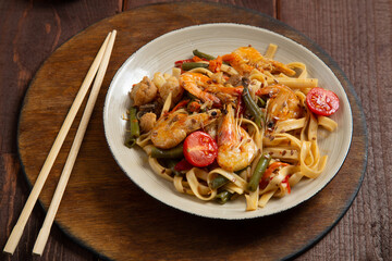 shrimp udon yaki soba sauce on a round stand next to soy sauce and chopsticks