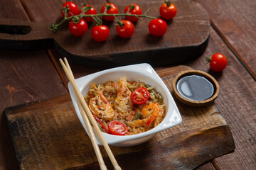 shrimp and rice yaki soba sauce next to cherry tomatoes soy sauce and chopsticks