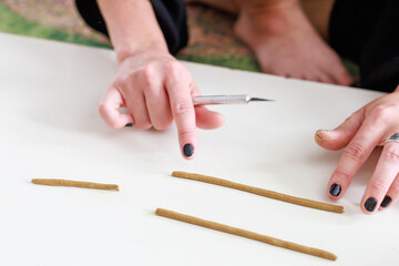 A woman makes an incense stick with her hands.