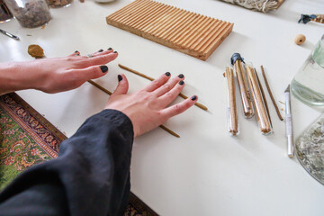 A woman makes an incense stick with her hands.