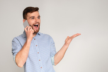 Come on. Handsome guy happy to hear good news talking on phone, studio background, panorama