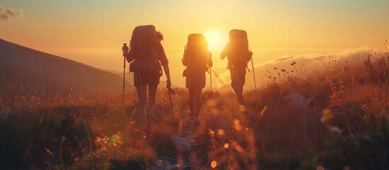 mountain climber with bag and stick at the top of the mountain during sunset