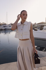 beautiful woman with dark hair in elegant classic clothes with accessories posing at the marina...