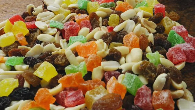 Mix of multi-colored dried fruits and nuts scattered on the surface, rotating in a circle. Medium plan