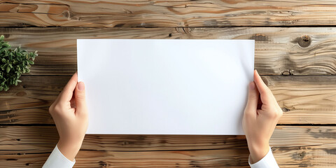 Top View of Hands Displaying White Paper on Wooden Background