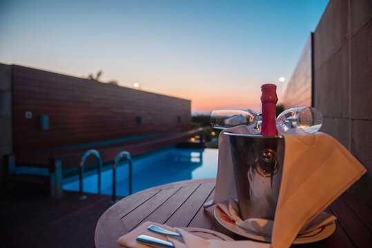 Late evening next to a private swimming pool drinking champagne