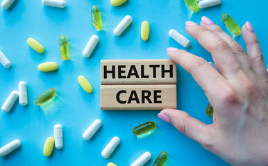 Healthcare symbol. Wooden blocks with words Healthcare. Beautiful blue background with pills. Doctor hand. Medicine and Healthcare concept. Copy space.