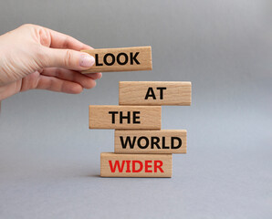 Look at the world wider symbol. Wooden blocks with words Look at the world wider. Beautiful grey background. Businessman hand. Business and Look at the world wider concept. Copy space.