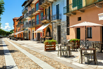 Narrow cobblestone street along old houses and outdoor restaurants in Cannobio, Italy.