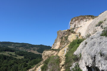 rock with waterfall over tuscan hills