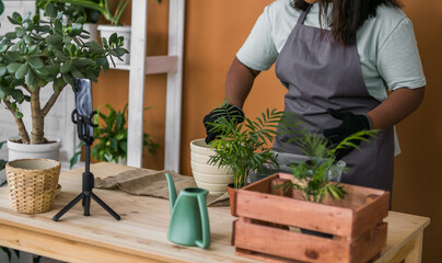 Banner close-up African american florist blogger filming tutorial video about transplanting plants...