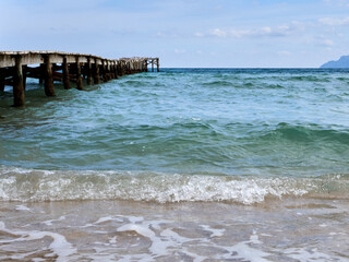 Wooden pier and waves in the  turquoise water of the Mediterranean sea. Muro Beach, Bay of Alcudia,...