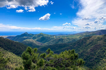 Clouds on blue sky over mountains and sea in Sierra de las Nieves National Park, Andalusia,...