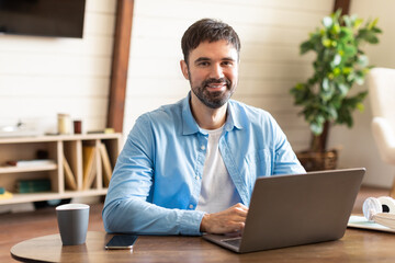 A man entrepreneur is seated at a table, engrossed in his laptop. He appears focused and concentrated on his work or task at hand.