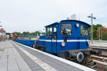 Eine Kleinlok älteren Baujahrs mit einem Arbeitszug am Bahnsteig