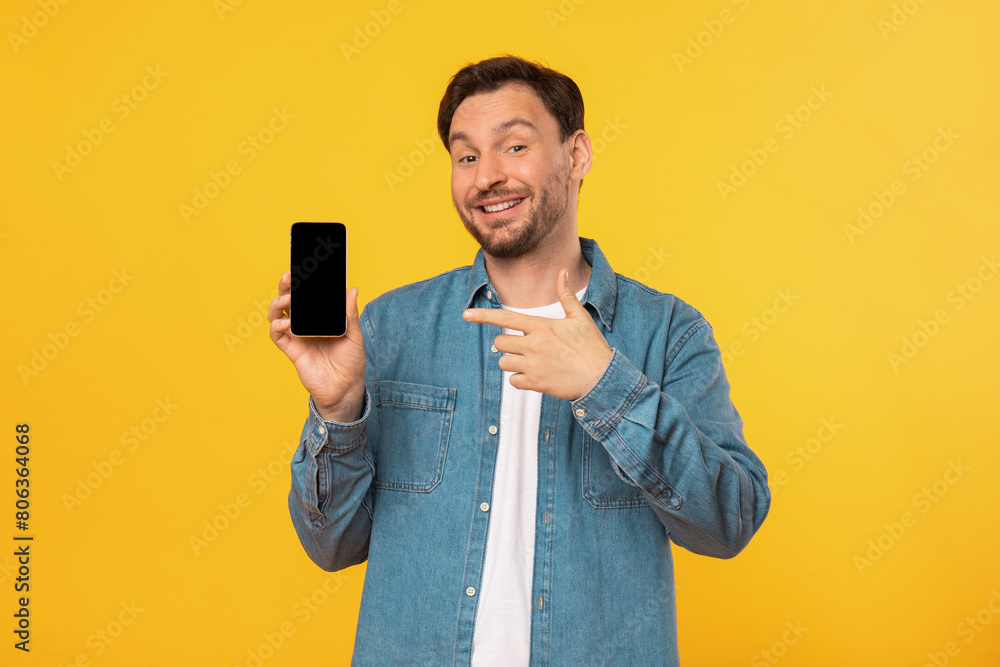 Poster a man wearing a blue shirt is holding a cell phone in his hand, looking at the screen with focus. th
